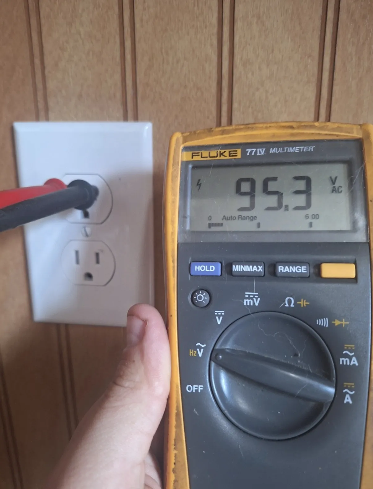 Multimeter voltage check on a household outlet during diagnosis