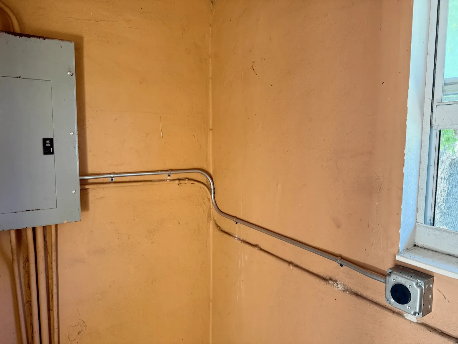 Exterior-mounted electrical panel with conduit runs on a building wall